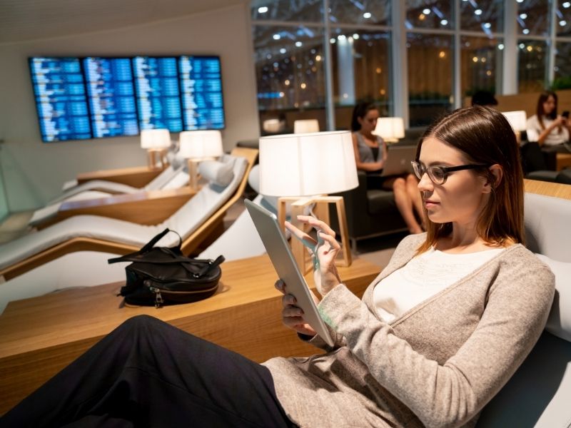 A woman working on a tablet in an airport lounge