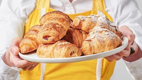 A photo of a person holding some croissants