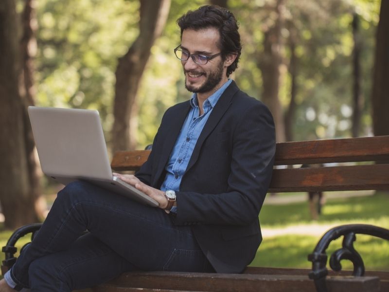 Man working on a laptop on a park bench