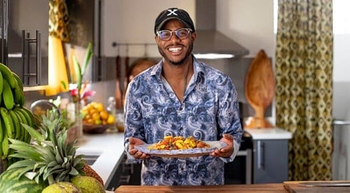 A photo of a smiling man holding a plate of food